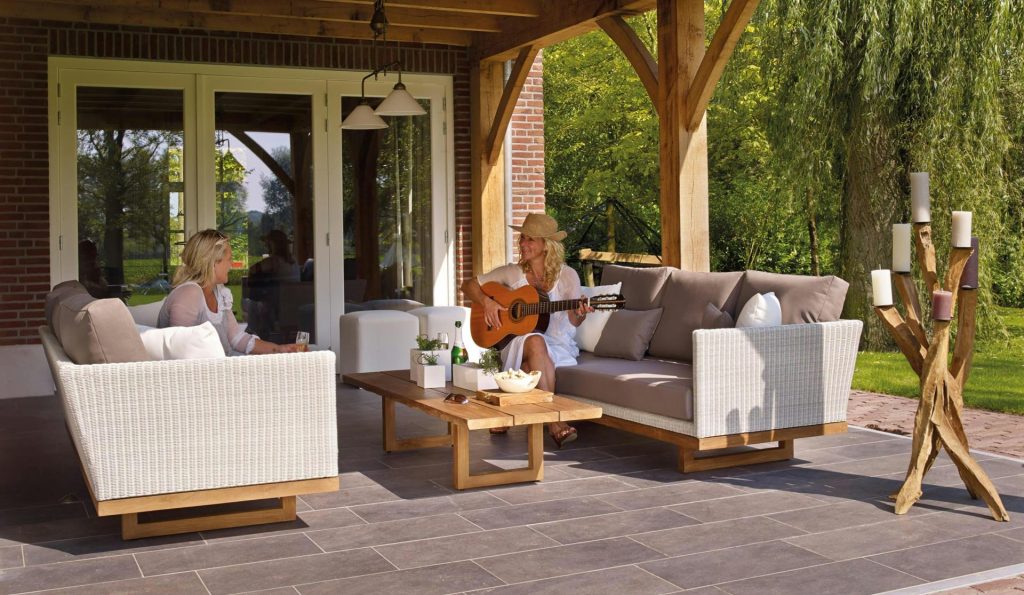 Two women enjoying a serene patio scene with a guitar and candles, surrounded by greenery.